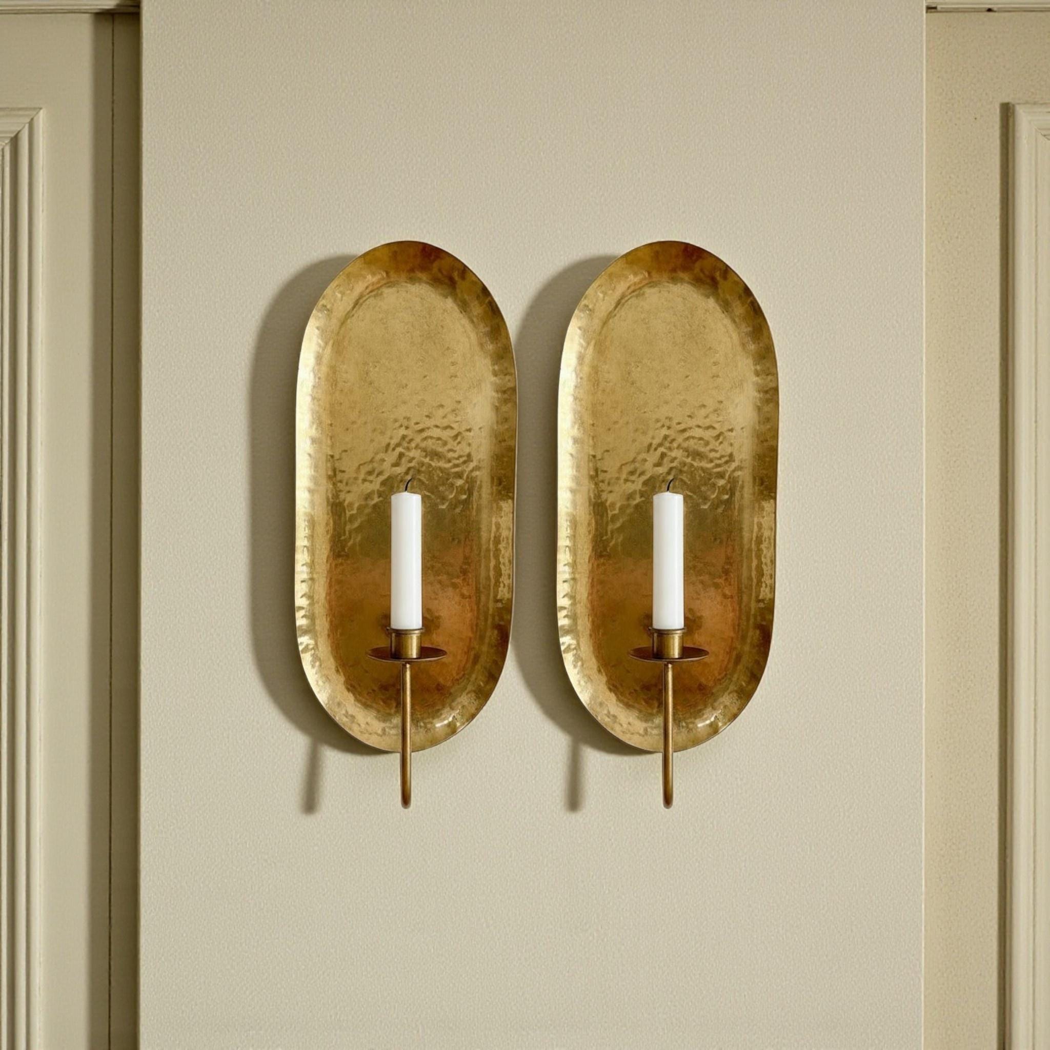 Add timeless elegance with this Antique Brass Wall Sconce set. Handmade from solid brass in Morocco, these decorative candle sconces feature a hammered oval backplate that brings warmth and artisan craftsmanship to modern, rustic, and Mediterranean interiors.
